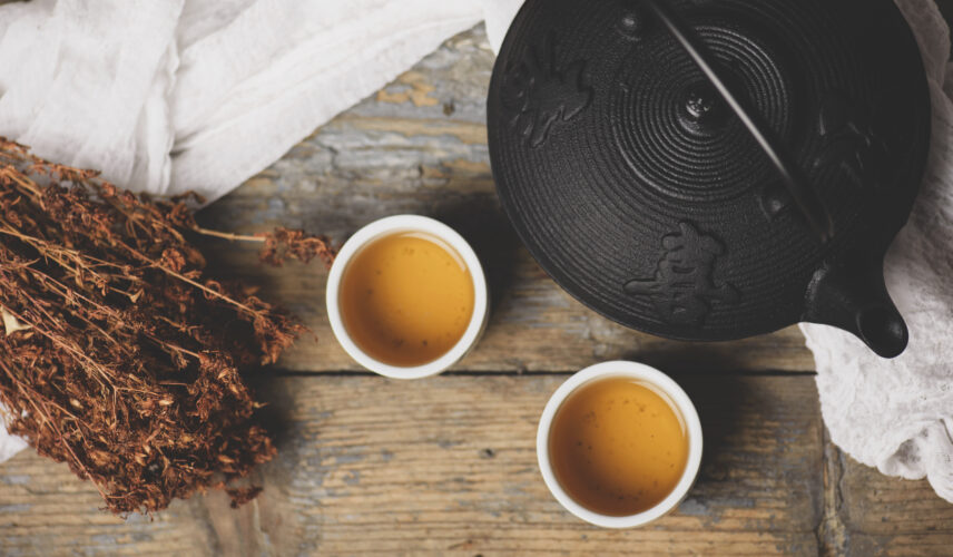 Traditional japanese herbal tea recipe prepared in cast iron teapot with organic dry herbs. Top view of asian traditional hot beverage on wooden table.