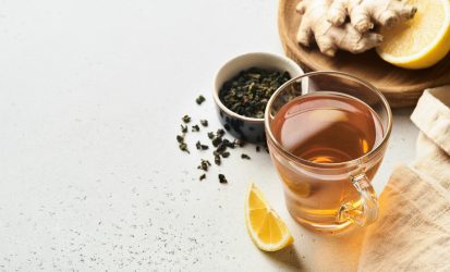 Ginger tea. Cup of ginger tea with lemon, honey and mint on grey background. Concept alternative medicine, natural homemade remedy for cold and flu. Top view. Free space for your text.