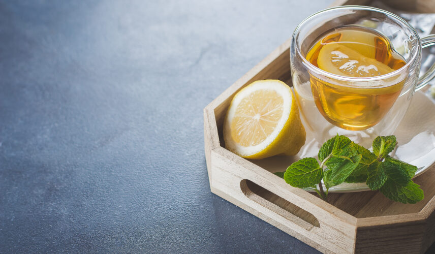 Medicines and Health Healthcare Concept. Cup of hot tea with lemons, pills and thermometer on wooden tray on concrete table background